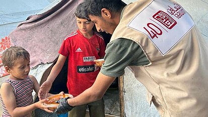 Kleines Kind in Gaza erhält warme Mahlzeit von Plan-Partner Taawon